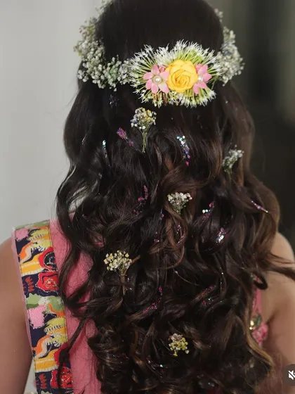 A romantic half up, half down hairstyle with soft waves. This look is beautifully decorated with a fresh floral crown and scattered baby's breath for a bohemian feel.