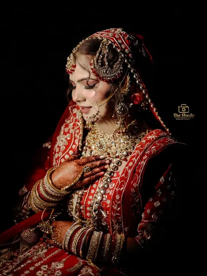 A powerful studio-style portrait of bride Simran. The dark background makes her red and gold lehenga pop, creating a timeless and dramatic image that focuses entirely on her.