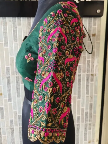 A side profile of the emerald green blouse, offering another angle of the intricate pink and gold embroidery that covers the sleeve.