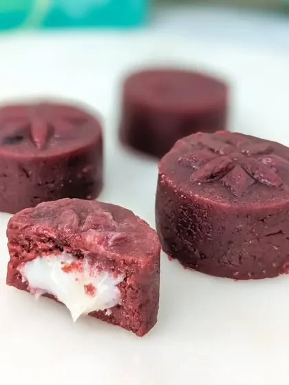 Our Red Velvet Cake Mithai, featuring the classic flavor with a cream cheese ganache filling, all wrapped in a beautiful deep red, flower-stamped design.