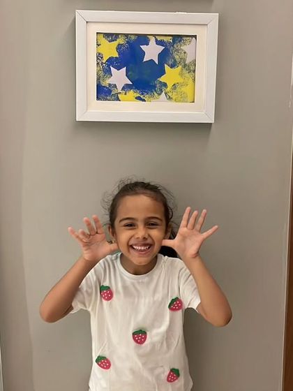 Amaira, age 5, posing with her framed abstract painting. Seeing their art properly displayed gives young artists a huge sense of accomplishment.
