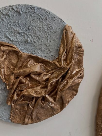 A close-up of a set of circular artworks made for a client in Dubai. This series combines a rough, grey, concrete-like texture with shimmering, sculpted gold fabric.