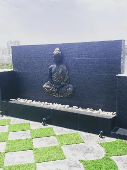 I specialize in creating tranquil, meditative spaces. This terrace features a custom-built water feature wall with a serene Buddha statue as the focal point, complemented by a unique checkerboard flooring pattern using artificial grass and patterned tiles.