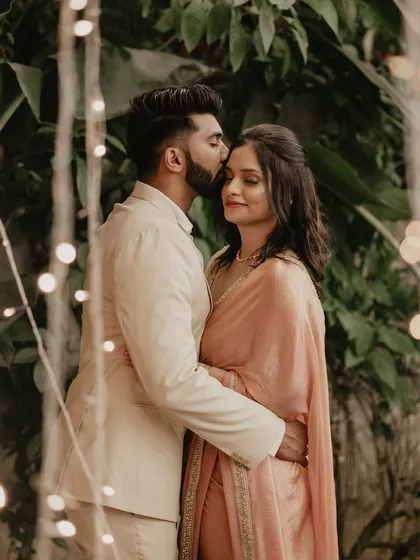 An intimate embrace during an engagement shoot, with soft bokeh from fairy lights creating a magical atmosphere. I focus on capturing the tender emotions of your special milestones.