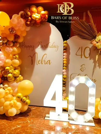Here's to being forty and fabulous. This vibrant 40th birthday decor uses warm yellow and gold tones, dual personalized backdrops, and marquee numbers to create a lively and celebratory atmosphere.