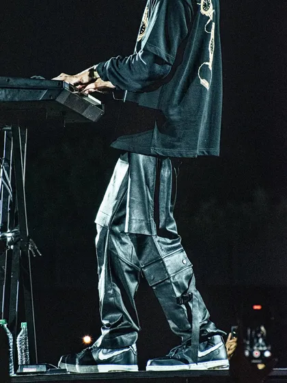A detailed shot focusing on Anirudh Ravichander's fashion, showing his stylish pants and Nike sneakers while he plays the keyboard.