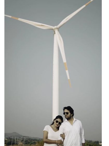 A classic couple portrait under a windmill, symbolizing their journey towards a new future together.