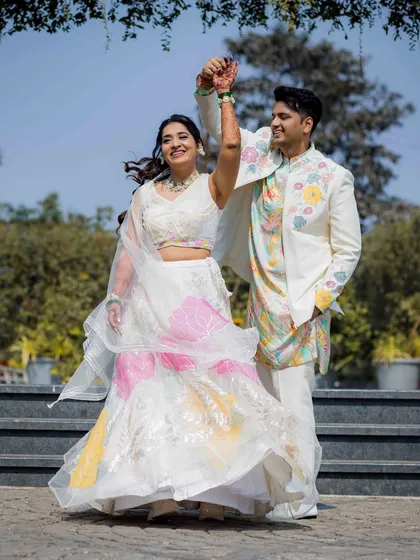 A dynamic shot of the couple dancing at their outdoor pre-wedding event. The bride's colorful lehenga twirls beautifully, capturing the movement and energy of the moment.