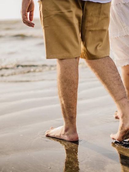 A close-up detail shot of the couple's feet on the wet sand, symbolizing their journey together.