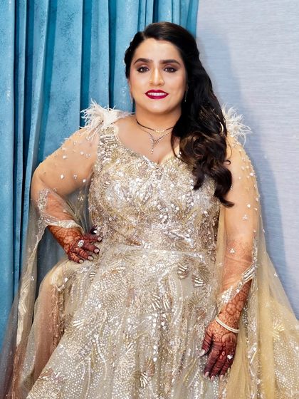 A full-length seated portrait. The bride's glamorous makeup and stunning gown create a look of unforgettable elegance for her wedding reception.