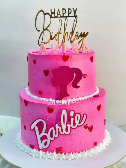 This two-tiered Barbie cake features a vibrant pink shimmer and the iconic Barbie silhouette. It's a fondant-free design that's both stylish and delicious with a white forest cake inside.