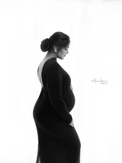 A duplicate of image 15, this monochrome portrait showcases the striking silhouette of a backless black gown against a clean, bright background for a modern and elegant feel.