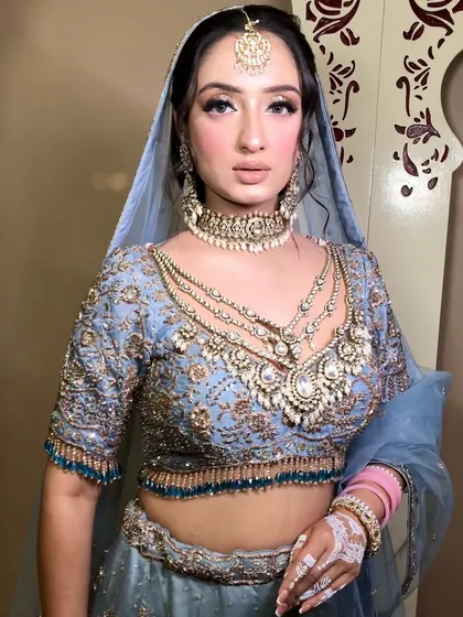 A close-up of this bride's pastel blue lehenga look, focusing on the layered kundan and pearl necklace and matching maang tikka.