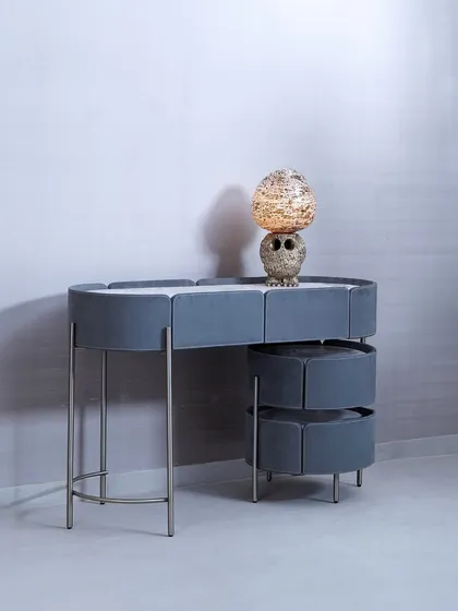 This modern console table features a unique, segmented design with soft grey upholstery and slender metal legs. The tiered, rotating drawers offer a creative storage solution, blending soft textures with a sleek, contemporary structure.