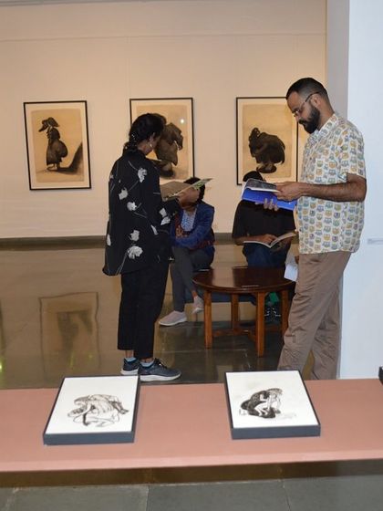 Visitors at the opening night of 'Quieter than Silence', examining the reverse paintings and drawings on display.