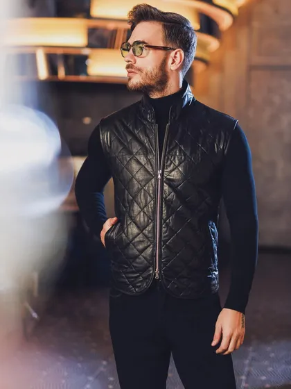 Layering is key to a dynamic wardrobe. Here, a quilted leather gilet adds texture and a modern edge to a simple turtleneck, creating a look that is both functional and stylish.