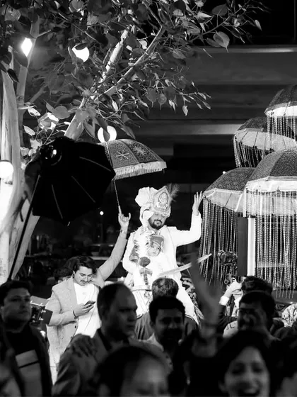 The groom's baraat procession captured in dramatic black and white. This style emphasizes the energy and movement of the crowd and the grandeur of the moment.