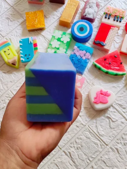 Holding the geometric soap to show its size, with a variety of other designs in the background.