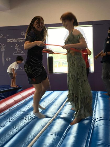 Even the adults can't resist the fun! Two moms enjoy a laugh while trying out a game on the Air Track during a birthday party.