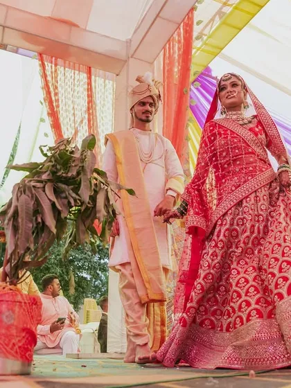 A low-angle shot of the couple at the mandap, emphasizing the bride's stunning red lehenga.