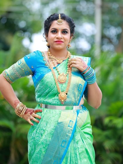 A confident pose showing off the full look. The makeup complements her traditional gold jewelry and vibrant saree.