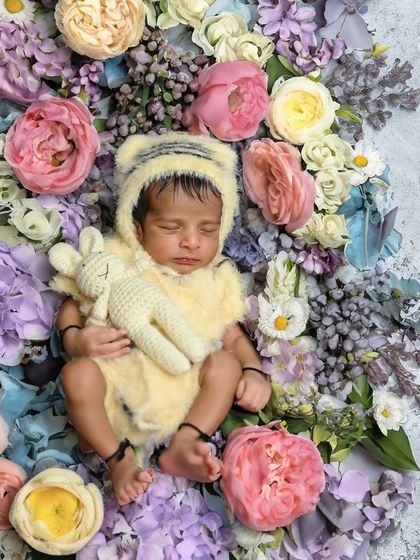 A newborn in a tiger-striped outfit, nestled in a wreath of flowers. This is a beautiful example of combining animal themes with soft, floral elements.