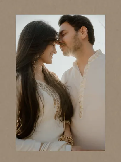 A close-up, sunlit portrait of a couple, their faces close together. The warm light and their gentle smiles create an image full of intimacy and affection.