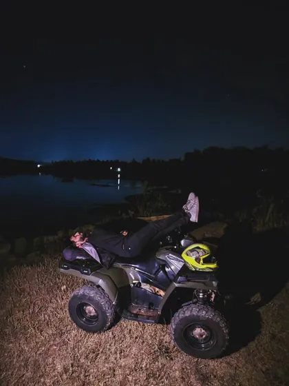 After an intense night ride, sometimes you just need to relax under the stars. A rider takes a moment to lie back on his ATV by the lake, soaking in the quiet of the night.