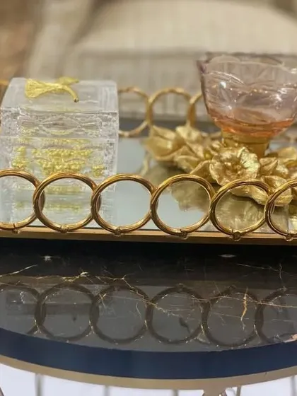 Our decorative metal trays are perfect for creating a luxurious gift hamper or as a standalone decor piece. This gold-finished tray with a mirrored base and circular details adds a touch of elegance to any setting.