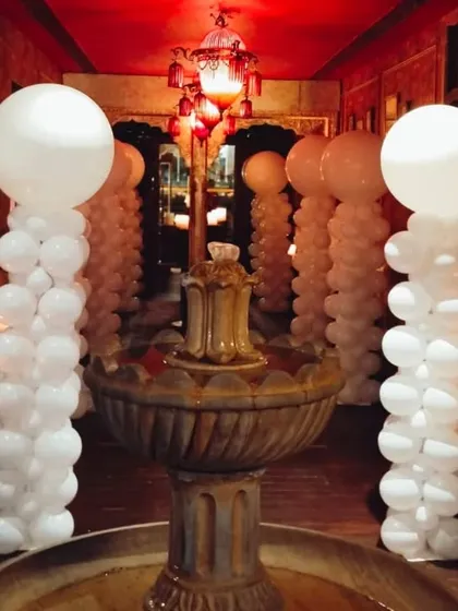 An elegant hallway decoration using classic white balloon pillars. The large round balloons on top add a modern and sophisticated touch.