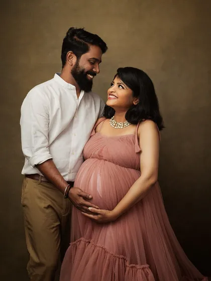 The shared glance between this couple is full of love and excitement. The soft pink tones of her dress add a gentle, romantic feel to their maternity portrait.