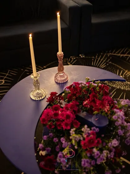 The details make the theme. We designed these crescent moon-shaped coffee tables and paired them with taper candles and jewel-toned floral arrangements to continue the celestial narrative throughout the space.