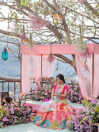 A wide shot of the bride on her beautifully decorated Mehendi seat, overlooking the hills of Jim Corbett.