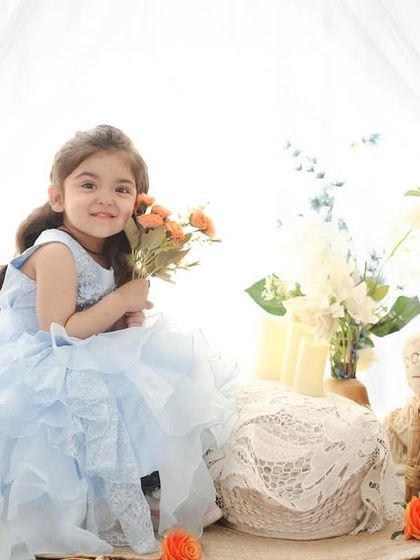 This sweet three-year-old is enjoying a pretend tea party in a dreamy, light-filled setting. The setup is perfect for capturing the imagination and personality of toddlers.