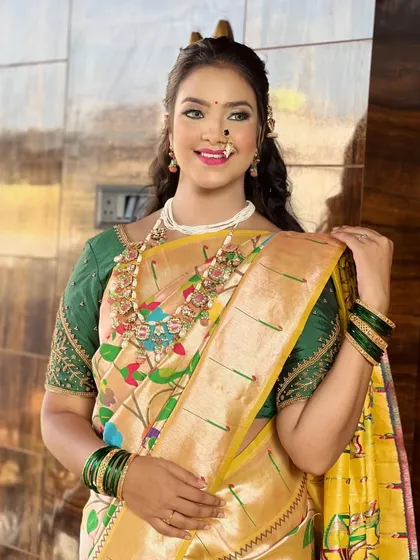 A happy bride showcasing her complete look in a yellow `Paithani` saree. The makeup features a bright lip and defined eyes, perfect for wedding day celebrations.