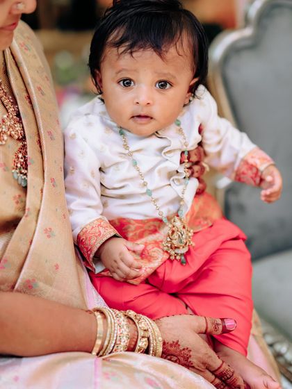 A close-up of my baby boy, looking adorable in his custom-made silk kurta and red pants, complete with a traditional necklace.