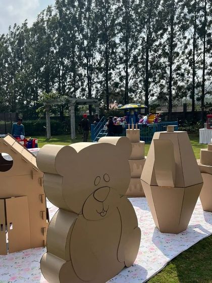 A different view of the 'Teddy Par-Tea' setup, showing the cardboard playhouse and giant teddy bear. These pieces are designed to be life-sized for toddlers, making them feel like they've stepped into a real teddy bear's world.
