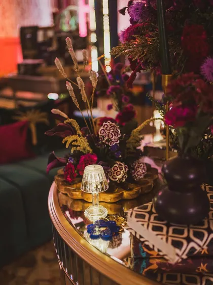 A close-up of a smaller floral arrangement, showing the rich color palette and the mix of textures, from the smooth vase to the feathery pampas grass.