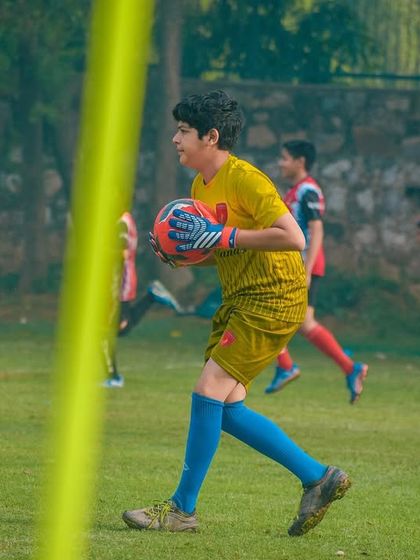 Our goalkeeper, focused and ready, prepares to distribute the ball after making a save during a Pride Cup match.