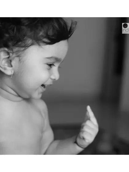A black and white candid shot of a toddler's happy expression. At-home sessions are great for capturing children in their most comfortable environment, resulting in genuine and relaxed portraits.