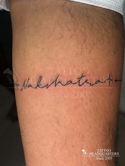 The name "Nakshatra" written in a delicate script that forms a line across the arm.