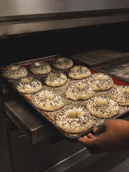 A tray of freshly baked everything bagels being pulled from the oven.