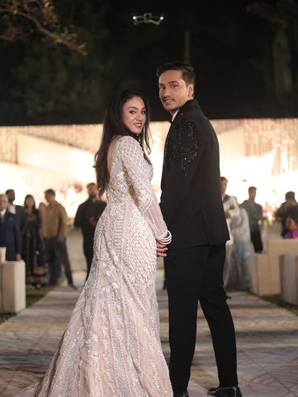 A beautiful shot of the couple from behind. The bride's romantic waves and the intricate details of her gown are on full display.