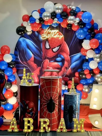 An action-packed Spiderman theme for a 5th birthday. The decoration features a dynamic backdrop of the superhero, balloon columns in red, blue, and black, and a large light-up marquee number '5'.