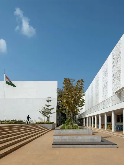 The open, stepped plaza at Vidyashilp Academy serves as a central gathering space for the school community. The design moves away from enclosed typologies, featuring partial-height walls and open walkways to promote natural cross-ventilation and a sense of openness.