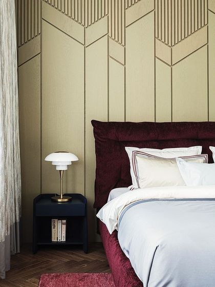 Luxury redefined. This bedroom combines a rich velvet headboard with a geometric-patterned wall panel, creating a sophisticated and visually interesting backdrop for the bed.