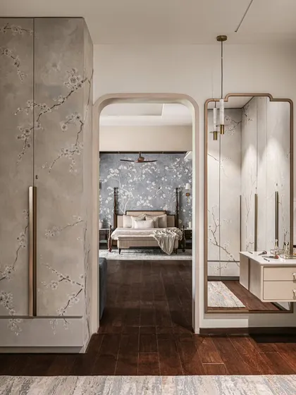 An arched opening reveals the master bedroom from the walk-in closet, where we continued the serene aesthetic with hand-painted floral motifs on the wardrobe doors and a custom vanity.