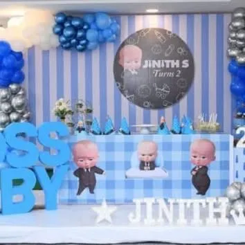 A detailed Boss Baby party with a blue and white striped backdrop and a custom circular sign. The setup includes 'BOSS BABY' block letters and multiple character cutouts.