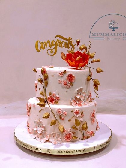 Congratulations are in order with this stunning two-tiered floral cake. The combination of delicate pink sugar flowers and gold leaf accents makes it a sophisticated choice for any milestone celebration.