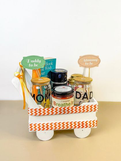 A 'Mommy to be' and 'Daddy to be' gift hamper, cleverly arranged in a decorative cart. This is a great example of creative styling for a baby shower gift.